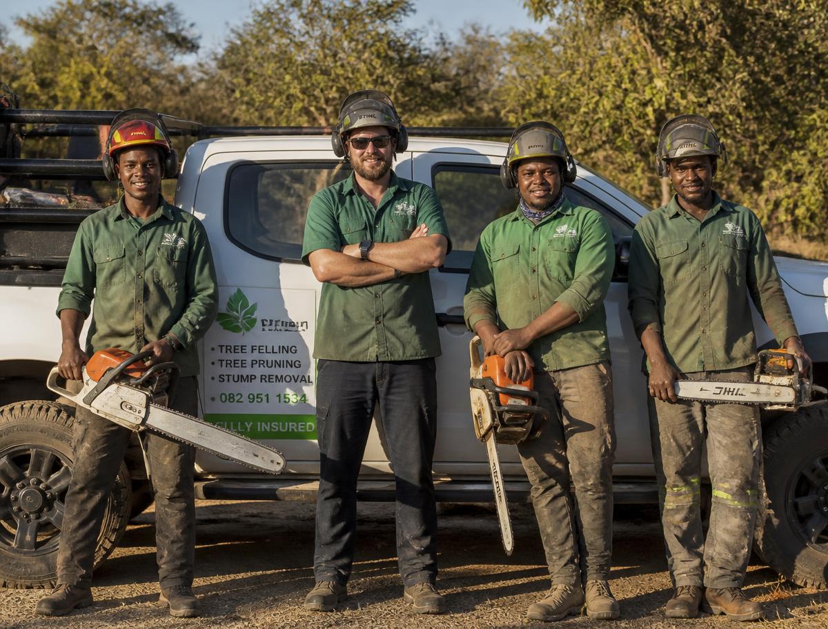 Tree felling crew with chainsaws beside their work vehicle